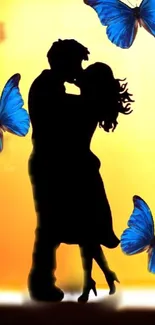 Romantic silhouette of couple with blue butterflies on an orange sunset background.