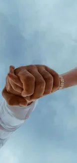 Couple holding hands against a serene blue sky background.