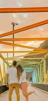 Couple walking on a colorful bridge at sunset.