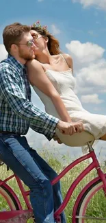 Romantic couple on a pink bicycle under a bright blue sky.