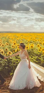 Couple in wedding attire walking through sunflower field under dramatic sky.