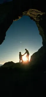 Silhouette of a couple at beach sunset under rock arch.