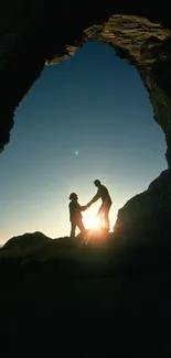 Silhouette of couple holding hands in a cave entrance during sunset.