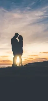 Silhouette of a couple embracing under a vivid sunset sky.