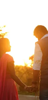 Couple holding hands at sunset, silhouetted against a golden sky.