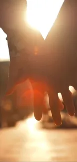 Silhouette of two hands holding against a bright sunset.