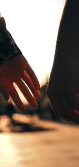 Hands touching at sunset, evoking romance.