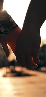 Couple holding hands at sunset, creating a romantic silhouette.