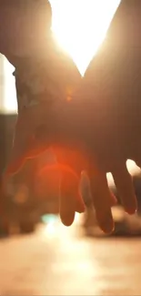 Couple holding hands at sunset with an orange glow.