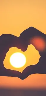 Hands forming a heart around a sunset.