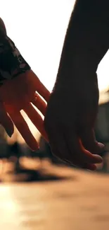 Silhouette of hands holding during sunset with warm peachy background.