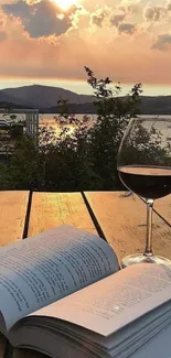 Open book, wine glass at sunset by lake.