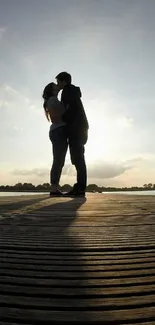 Silhouette of a couple embracing at sunset on a wooden dock.