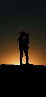 Silhouette of a couple against a sunset backdrop.