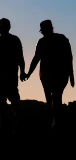 Silhouette of a couple holding hands against a sunset sky.