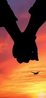 Romantic sunset silhouette of couple holding hands.