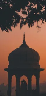 Romantic silhouette under dome at sunset with orange sky.