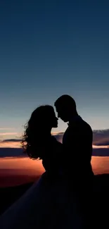 Couple silhouetted against a vibrant sunset sky.