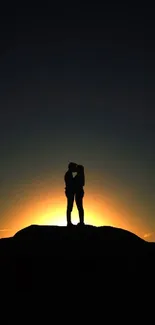 A romantic silhouette of a couple against a sunset backdrop on a dark horizon.