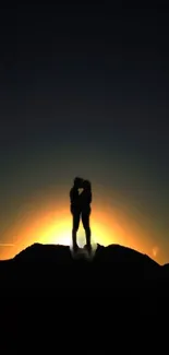 Silhouette of a couple kissing at sunset with glowing orange sky.