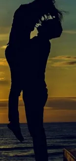 Silhouette of a couple embracing at sunset on a beach.