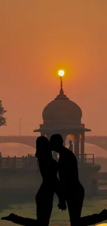 Romantic couple silhouette at sunset with vibrant orange sky.