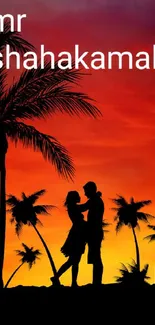 Silhouette of a couple beneath palm trees at a vibrant orange sunset.