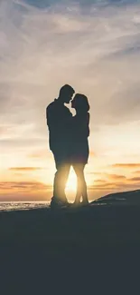 Silhouetted couple embracing at sunset on the beach wallpaper.