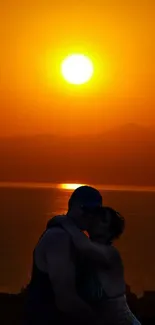 Romantic silhouette of a couple against an orange sunset over the ocean.