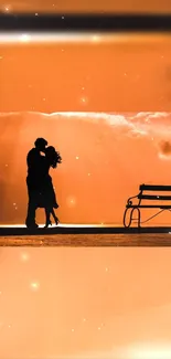 Romantic silhouette of couple at sunset with an orange sky and peaceful bench.