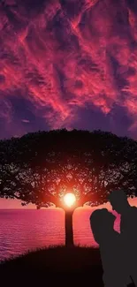 Romantic sunset silhouette with couple under tree.