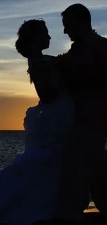 Silhouette of a couple at sunset by the ocean.