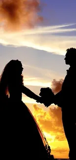 Silhouette of a couple holding hands at sunset with vibrant sky.