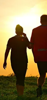 Couple walking at sunset over a grassy field, silhouetted against a golden sky.