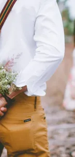 Person holding flowers behind back, romantic setting.