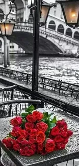 Red roses on a Venice table with a scenic bridge view.