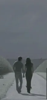 Couple holding hands on a serene gray path.