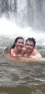 Couple enjoying a swim beneath a serenely flowing waterfall.