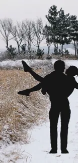 Silhouette of couple on snowy winter path with trees.