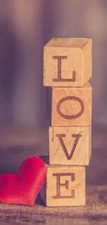 Wooden blocks spelling LOVE beside red heart.