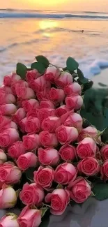 A bouquet of pink roses on a beach at sunset with waves in the background.