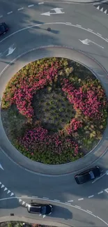 Aerial view of a roundabout with flower center and surrounding cars.