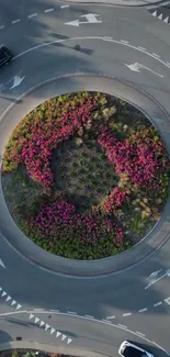 Aerial view of roundabout with pink flowers and greenery in a vibrant landscape.