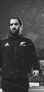 Rugby player walking in rain with intense focus in black and white.