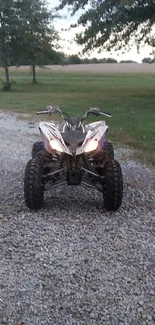 ATV on gravel path in countryside with trees.