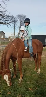 Two riders on a chestnut horse in a rural setting.