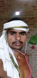 Portrait of a man in traditional rural attire with a brick wall background.