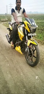 Man riding yellow motorcycle on rural path.