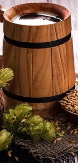 Rustic wooden beer mug with hops and barley on a textured surface.