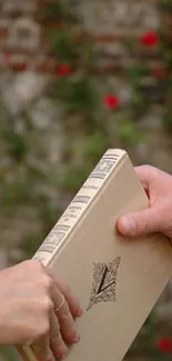 Two hands passing a book, rustic background.